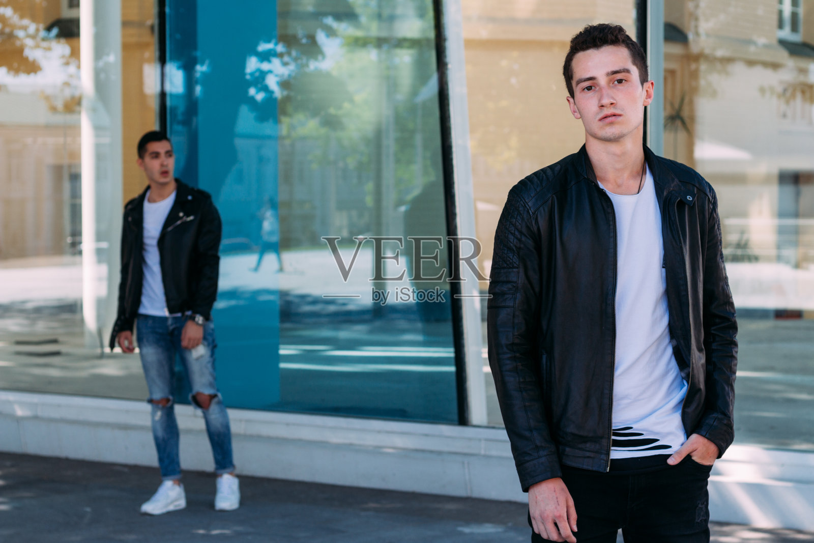 有魅力的帅哥站在城市里，摆姿势。在镜子建筑附近照片摄影图片