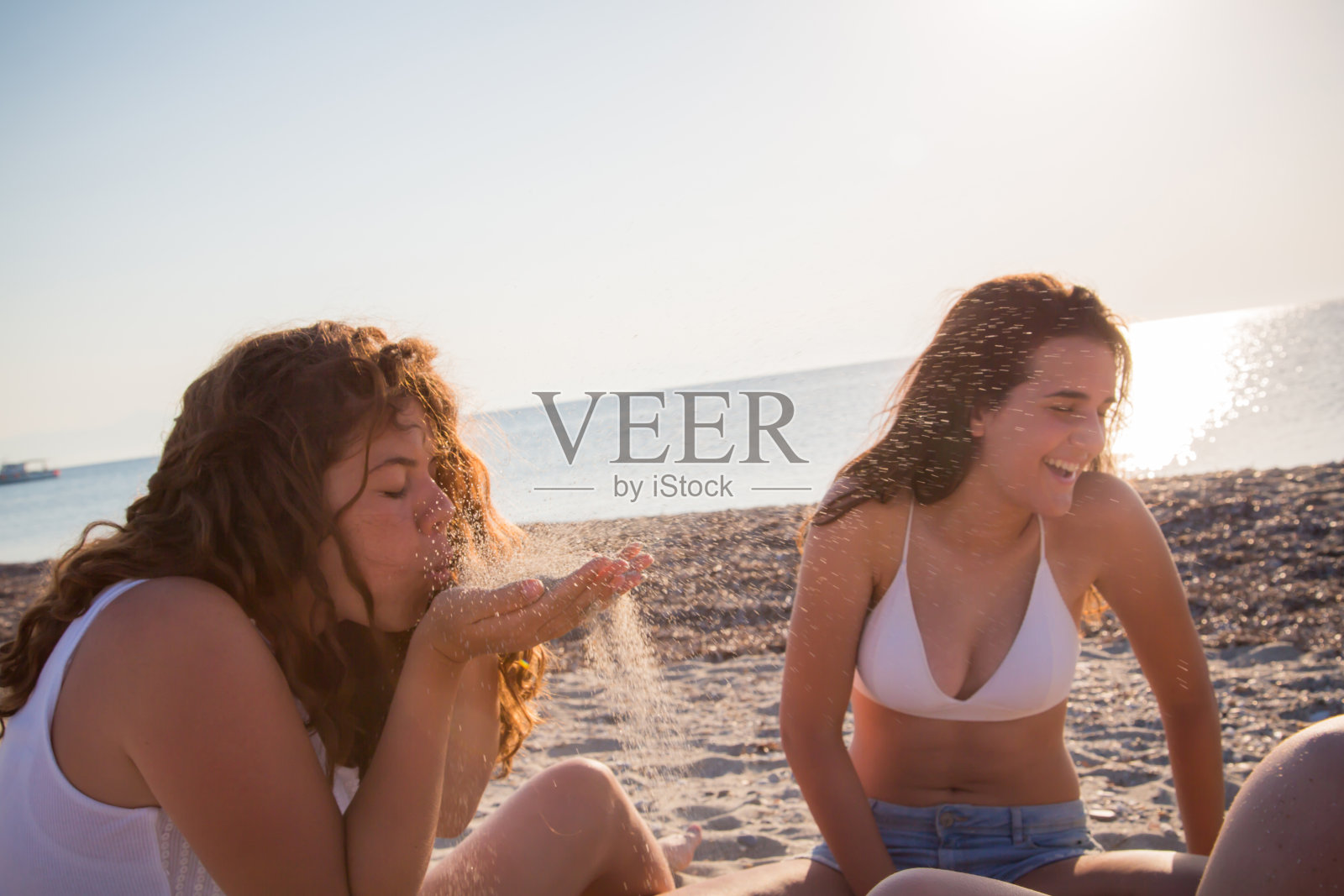 青少年女性在希腊海滩上玩沙照片摄影图片