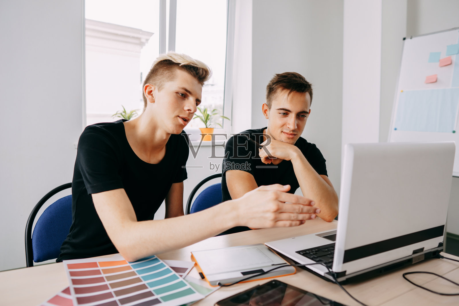 两个年轻人看着笔记本电脑显示器讨论照片摄影图片