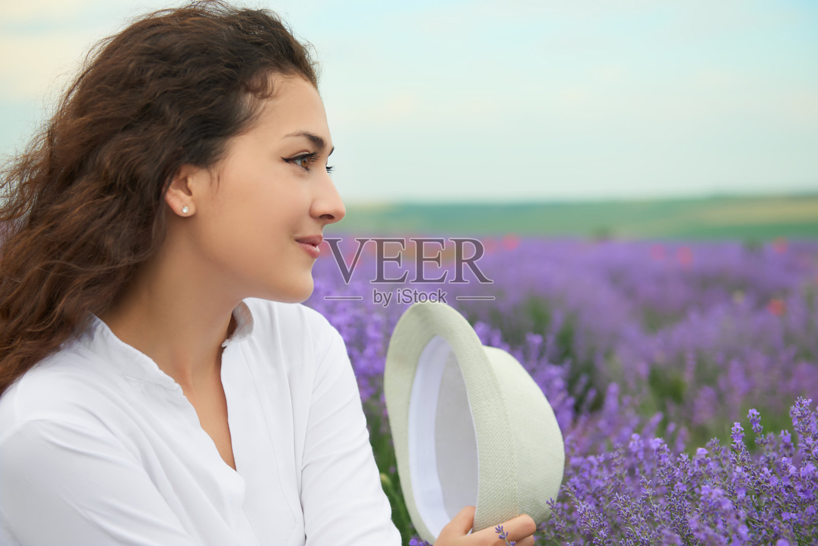 年轻女子是在薰衣草田里，美丽的夏日风景中盛开着红色的花照片摄影图片