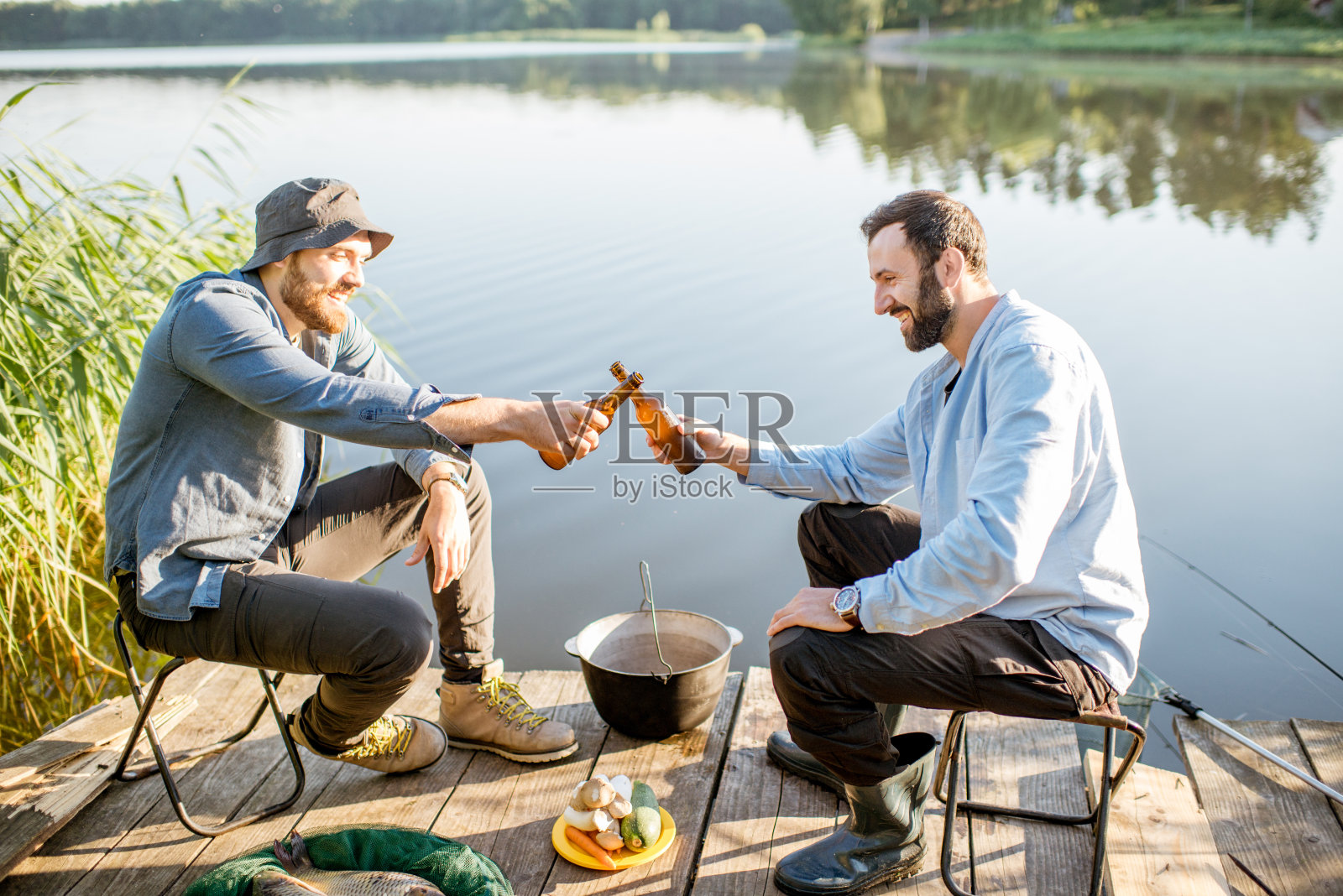 男人们在湖边钓鱼，喝着啤酒放松照片摄影图片