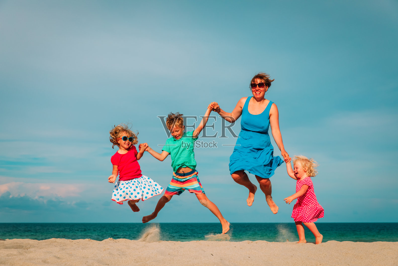妈妈和孩子们有乐趣在热带海滩跳照片摄影图片