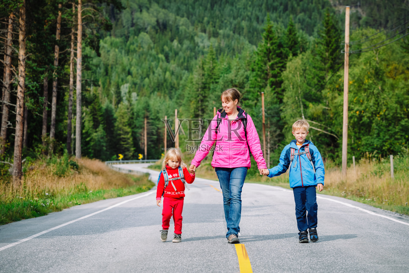 母亲带着两个孩子在大自然的路上旅行照片摄影图片