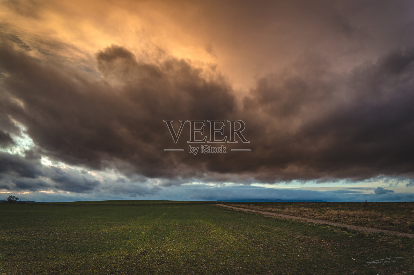 乌云在长满绿草的草地上倾盆而下照片摄影图片