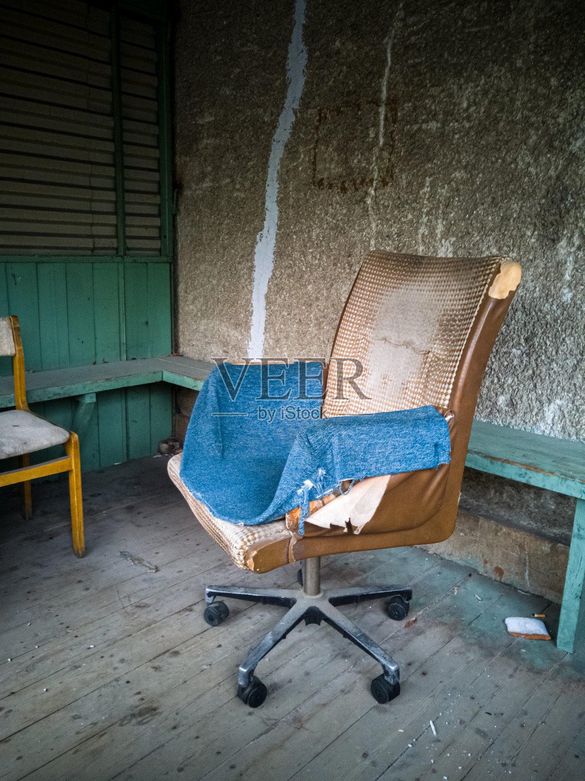 在粗糙的混凝土墙上，有一把脏兮兮的老式扶手椅，上面盖着一块蓝色的破布照片摄影图片