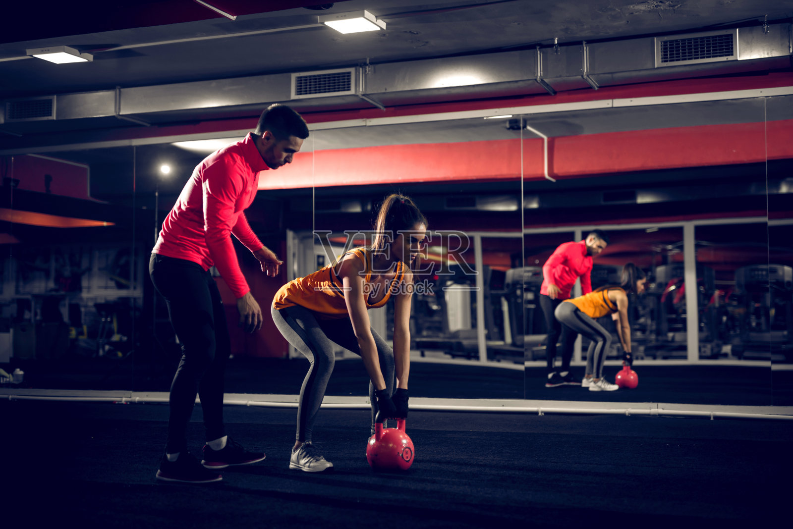 私人教练在健身房帮助她的客户举重。照片摄影图片