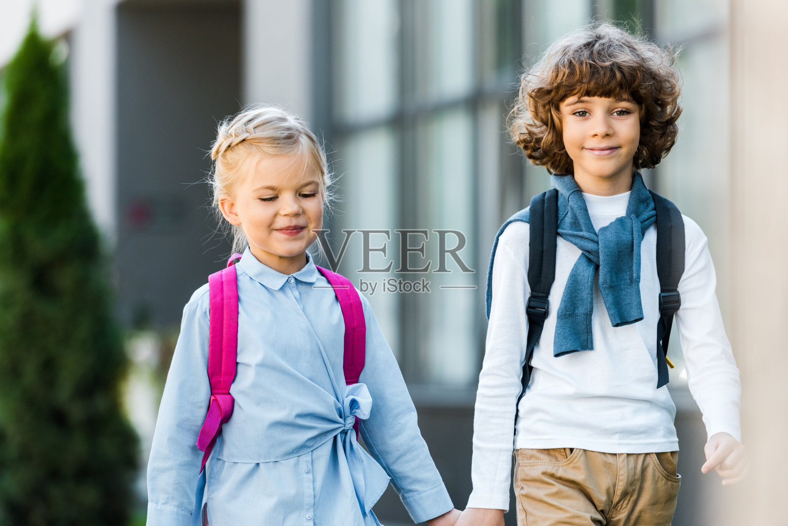 可爱的孩子背着书包，手牵着手一起走路照片摄影图片
