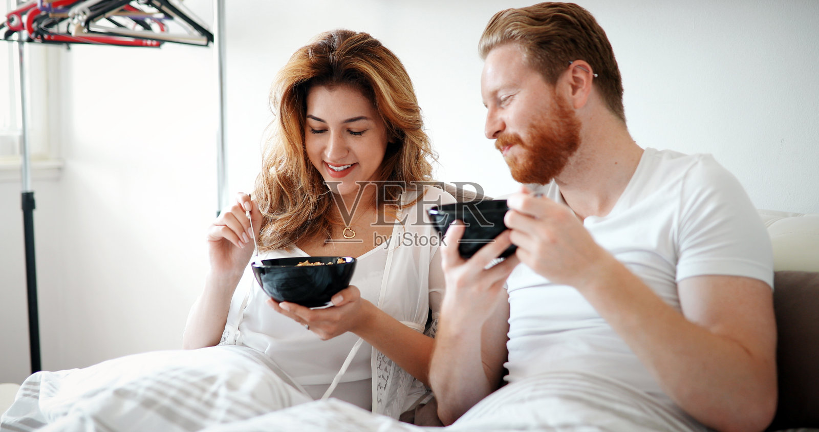 年轻迷人的夫妇在床上吃早餐照片摄影图片