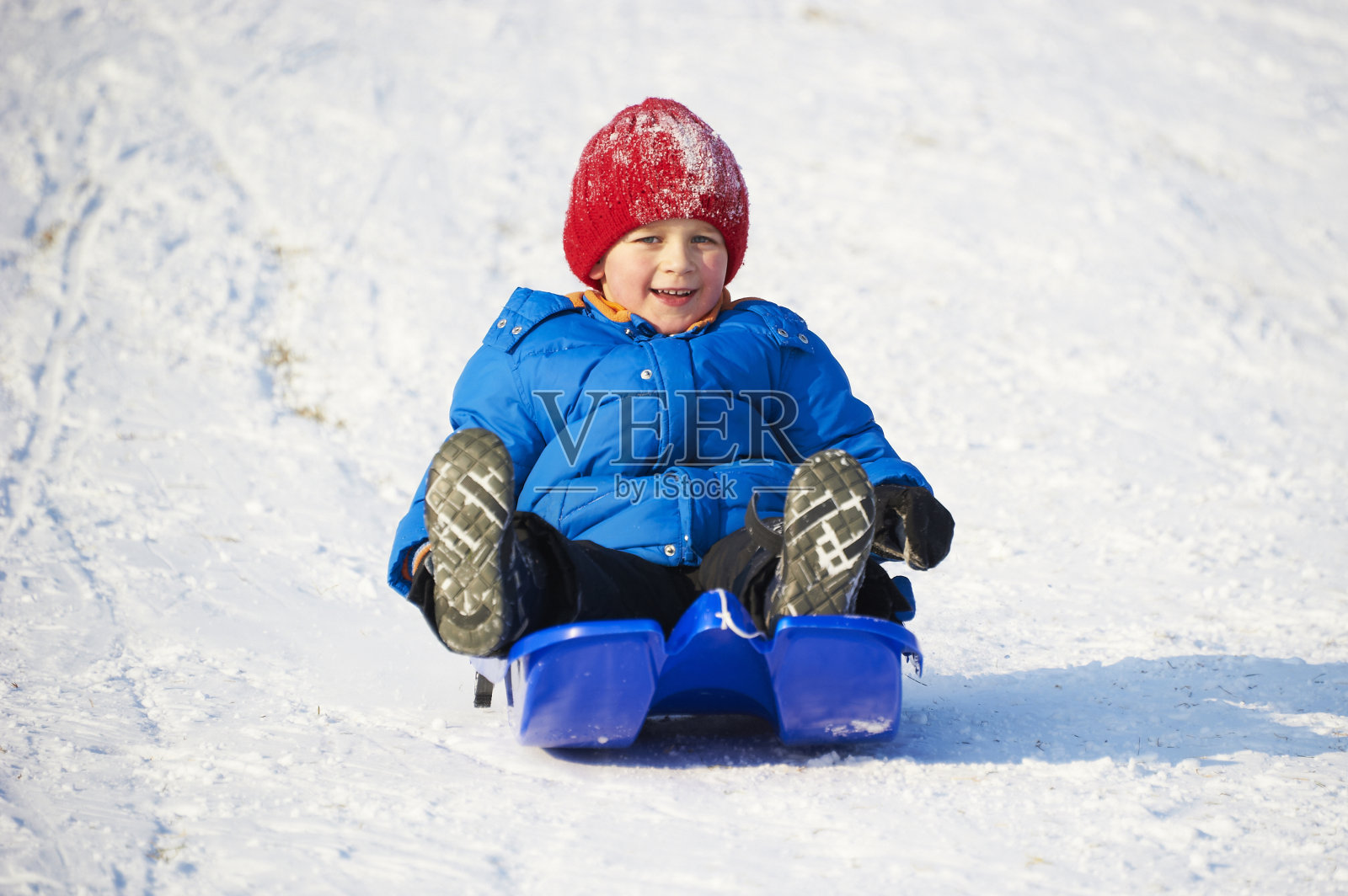 一个骑雪橇的小男孩。照片摄影图片