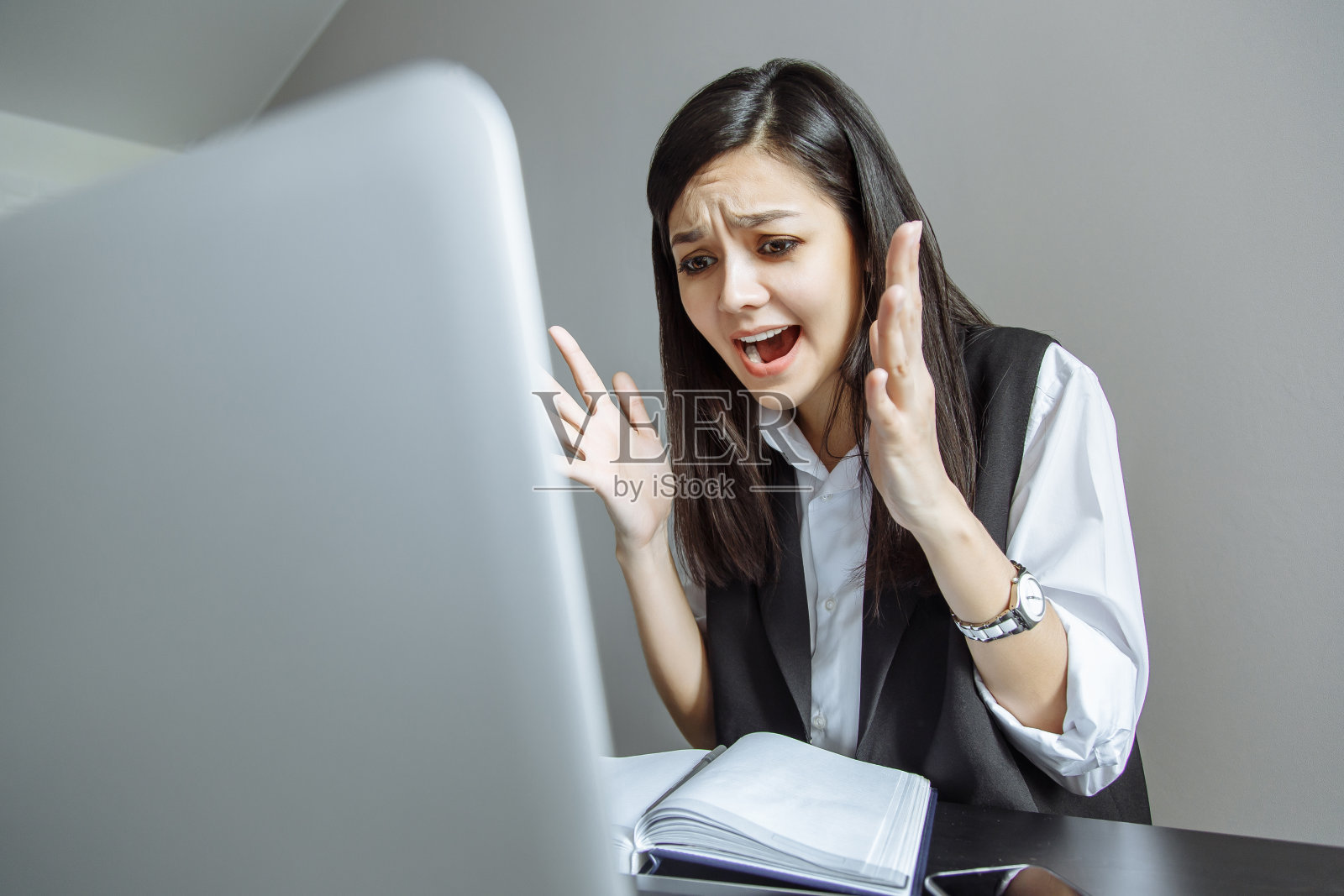 情绪化的女商务人员对着笔记本电脑大喊大叫。在办公室里度过充满压力的一天照片摄影图片