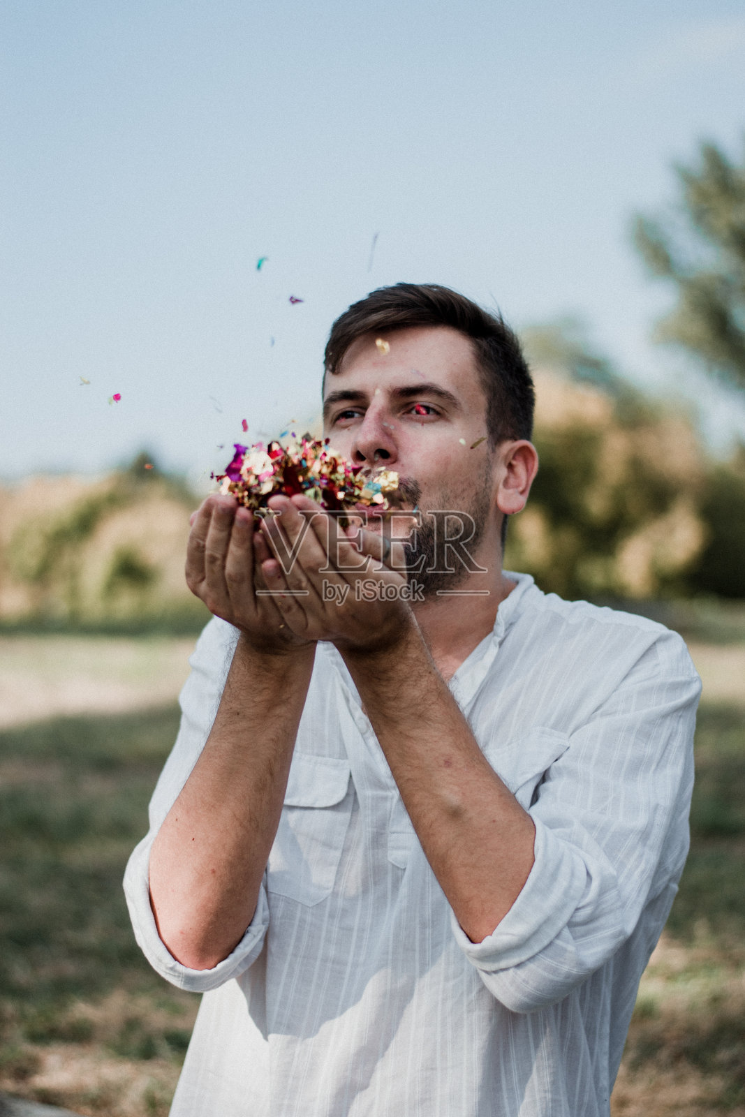年轻男子吹五彩纸屑的肖像照片摄影图片