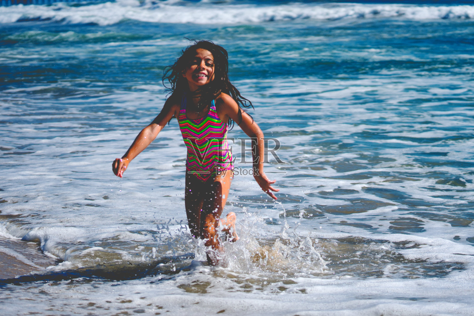 美丽的8岁西班牙女孩在海滩上玩耍照片摄影图片