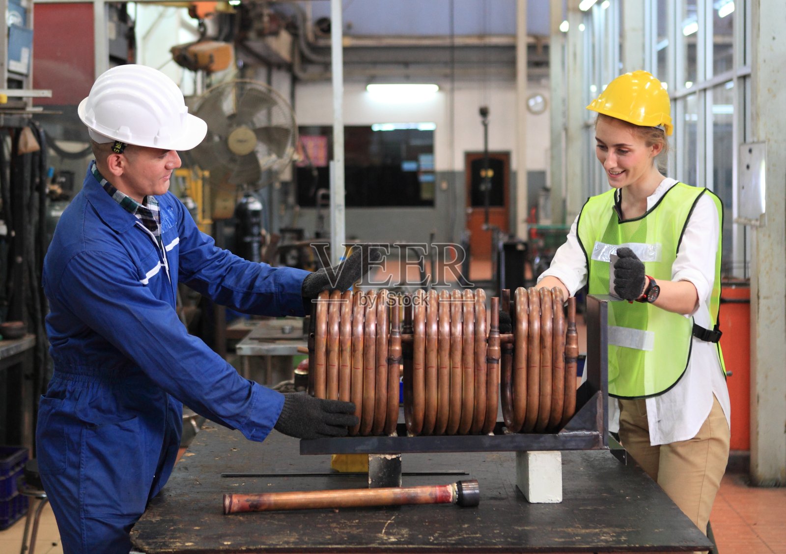 男和女工业工程师在现场工作时讨论新项目。他们在一家重工业制造厂工作。照片摄影图片