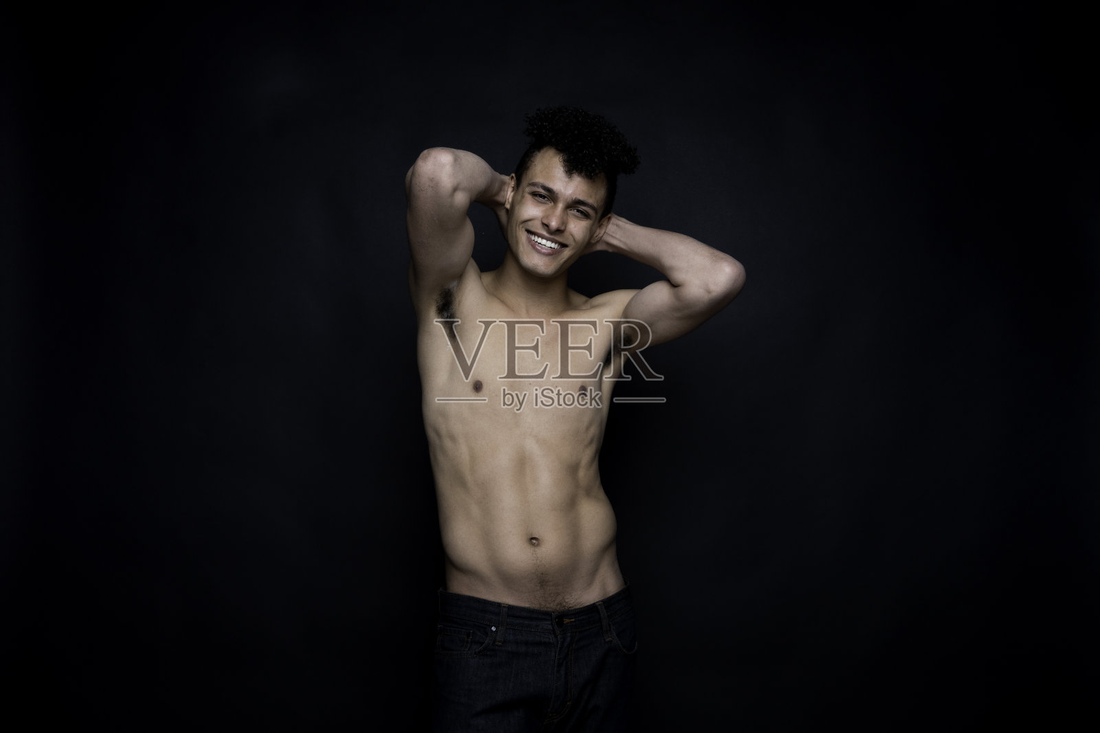 非洲裔男性潮人穿着牛仔裤站在黑色背景前照片摄影图片