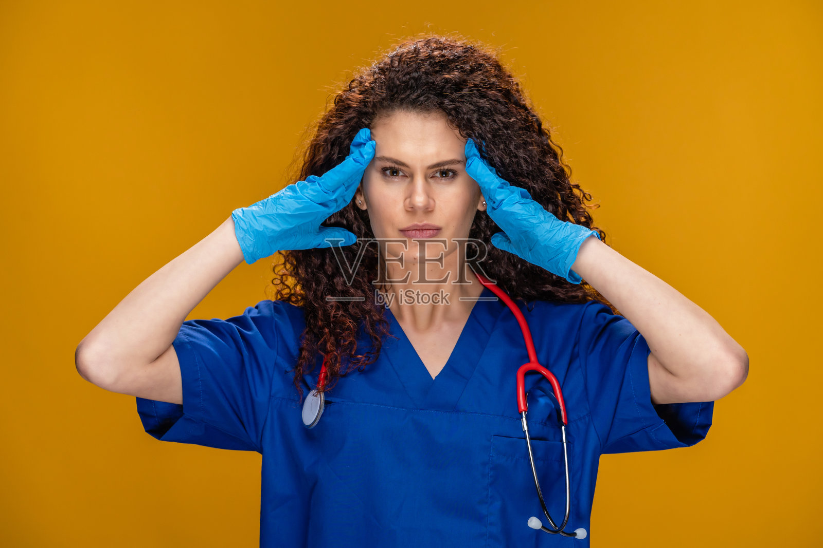 沮丧的年轻女医生头痛看着黄色背景的摄像机照片摄影图片