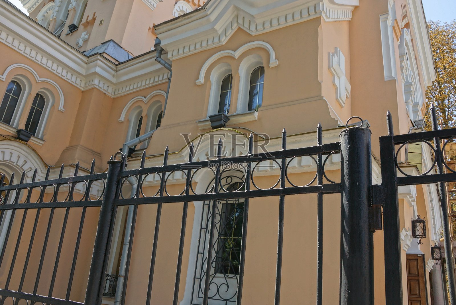 棕色的混凝土墙前面有锋利的铁条组成的黑色金属栅栏照片摄影图片