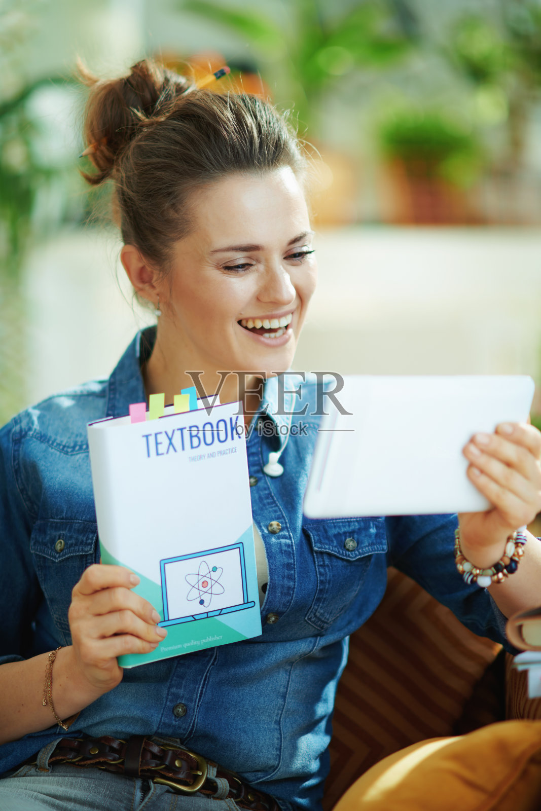 在阳光明媚的日子里，微笑的女性在现代的房子里展示教科书照片摄影图片