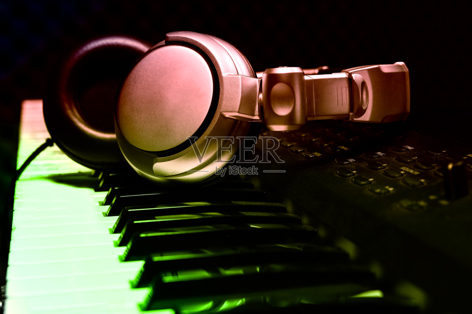 钢琴键盘用耳机播放音乐，耳机上有钢琴键盘，耳机上有电子钢琴背景，由乐器伴奏。照片摄影图片