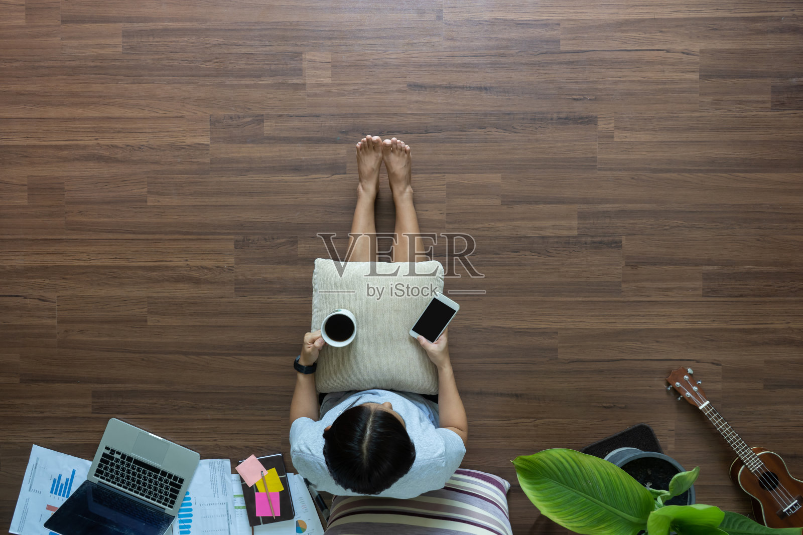 顶视图女人放松使用智能手机和喝咖啡在木地板上，在家工作的想法概念照片摄影图片