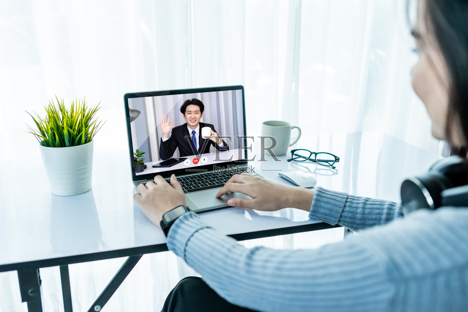 亚洲商务女性戴着耳机喝着咖啡，享受着在笔记本电脑或笔记本电脑和智能手机上观看教育网络研讨会。微笑聊天，与客户合作伙伴视频通话。照片摄影图片