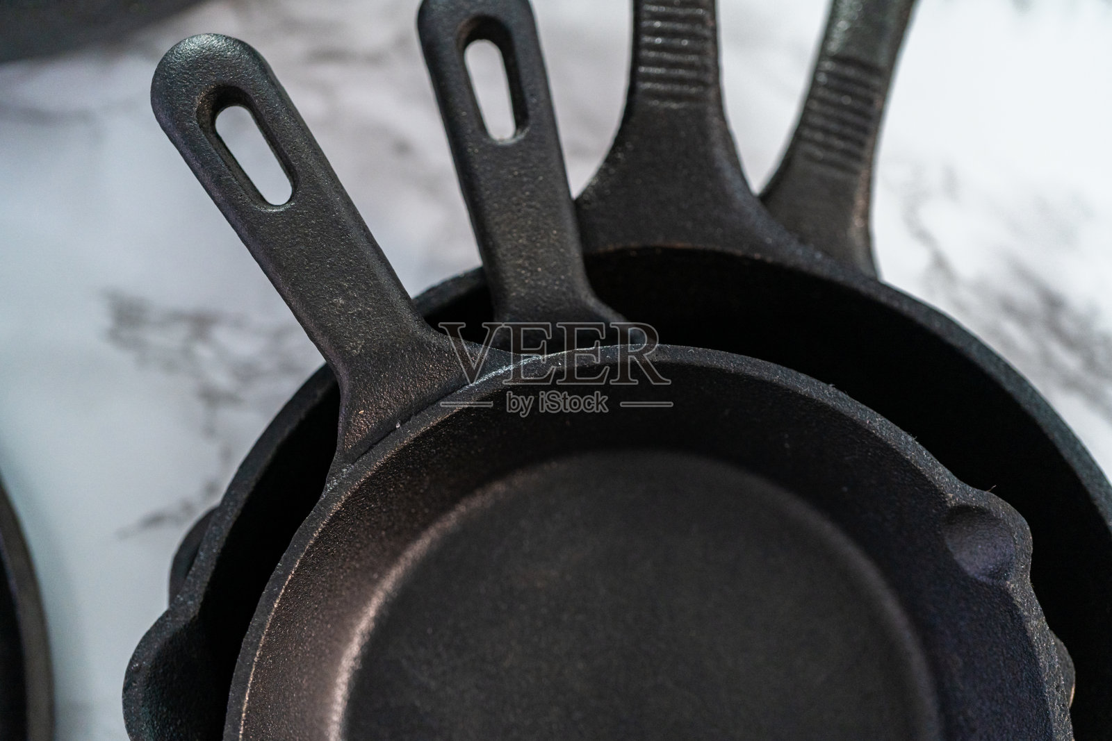 大理石背景上的各种铸铁煎锅。照片摄影图片