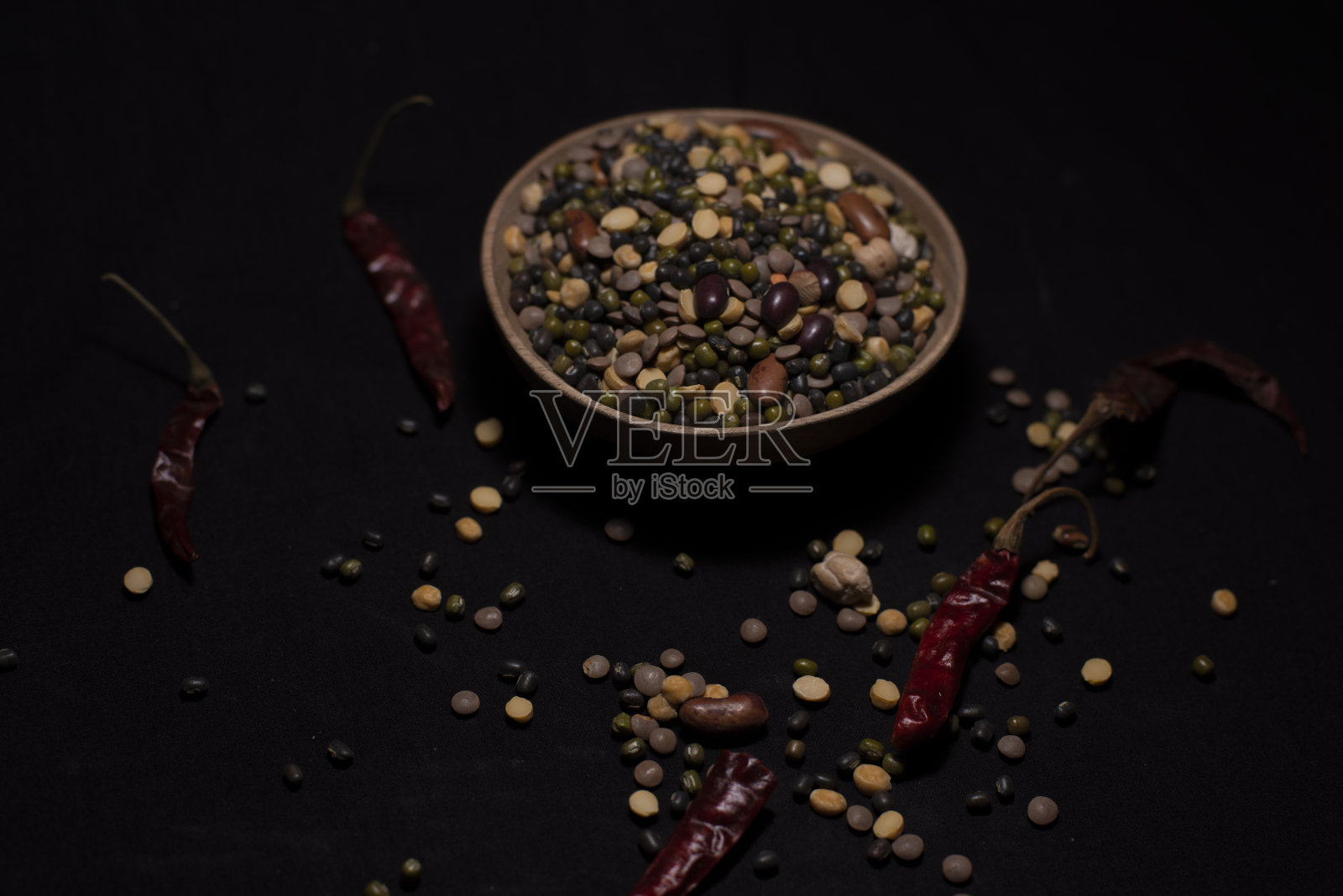 一碗印度混合豆类装饰谷物和干辣椒在黑暗的复制空间背景。照片摄影图片