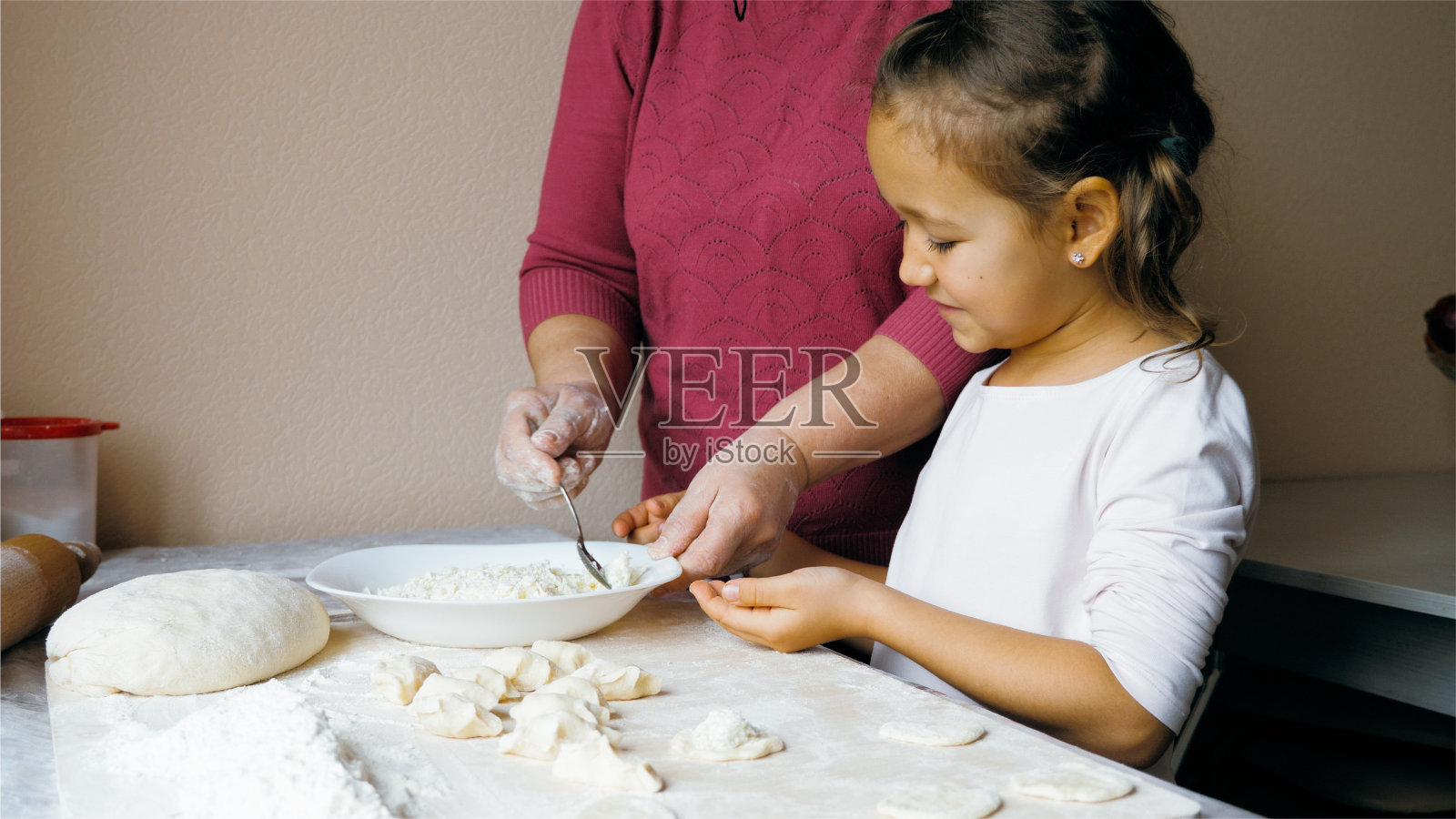 祖母和孙女正在家里的厨房里用奶酪包饺子照片摄影图片