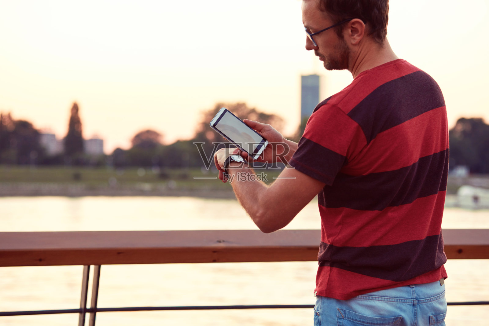 一名男子在手腕上看时间，在户外使用手机。照片摄影图片