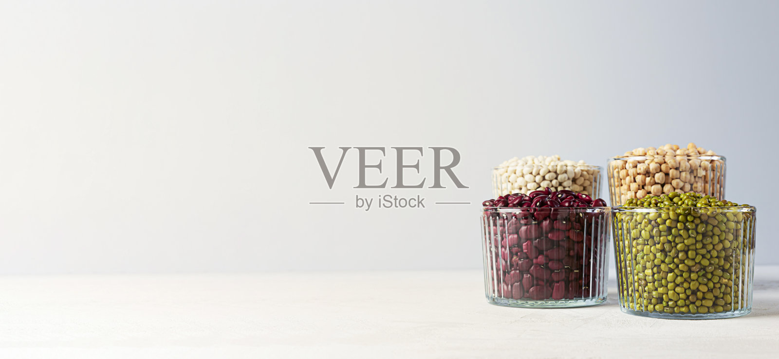 碗各种豆类:鹰嘴豆，扁豆，绿豆，红豆和白豆在灰色的背景与复制空间。横幅照片摄影图片