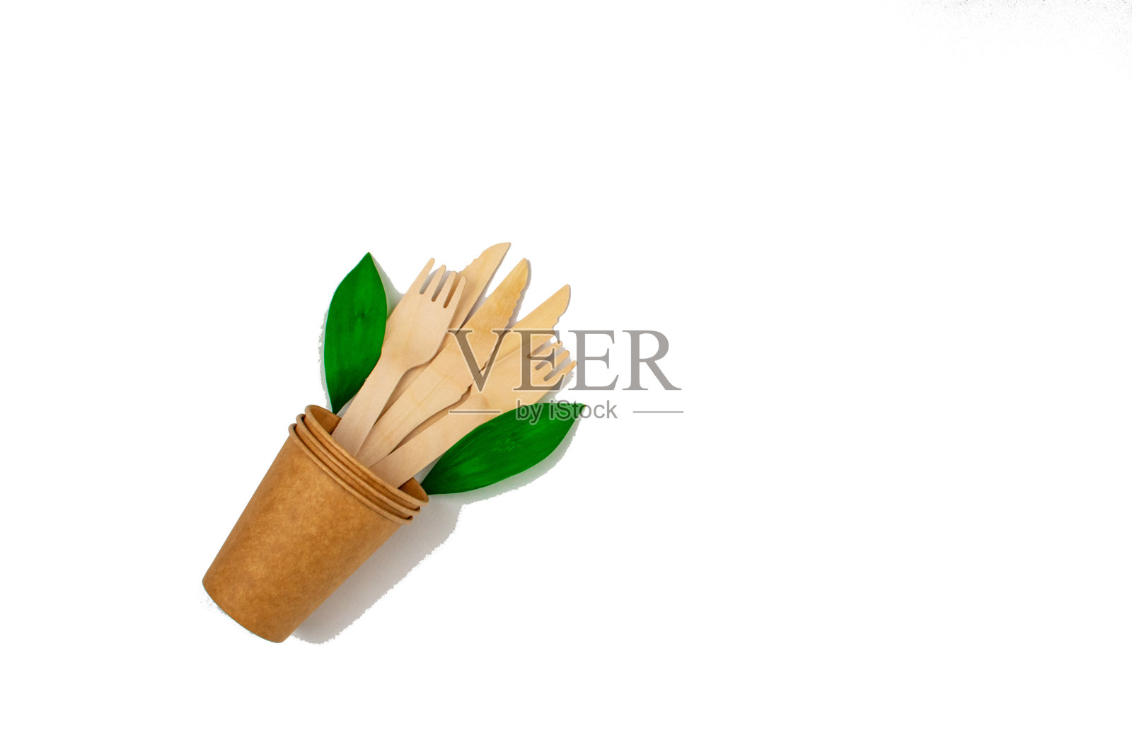 “零浪费”的概念。刀叉装在纸杯里，背景是白色。绿色的传单。照片摄影图片