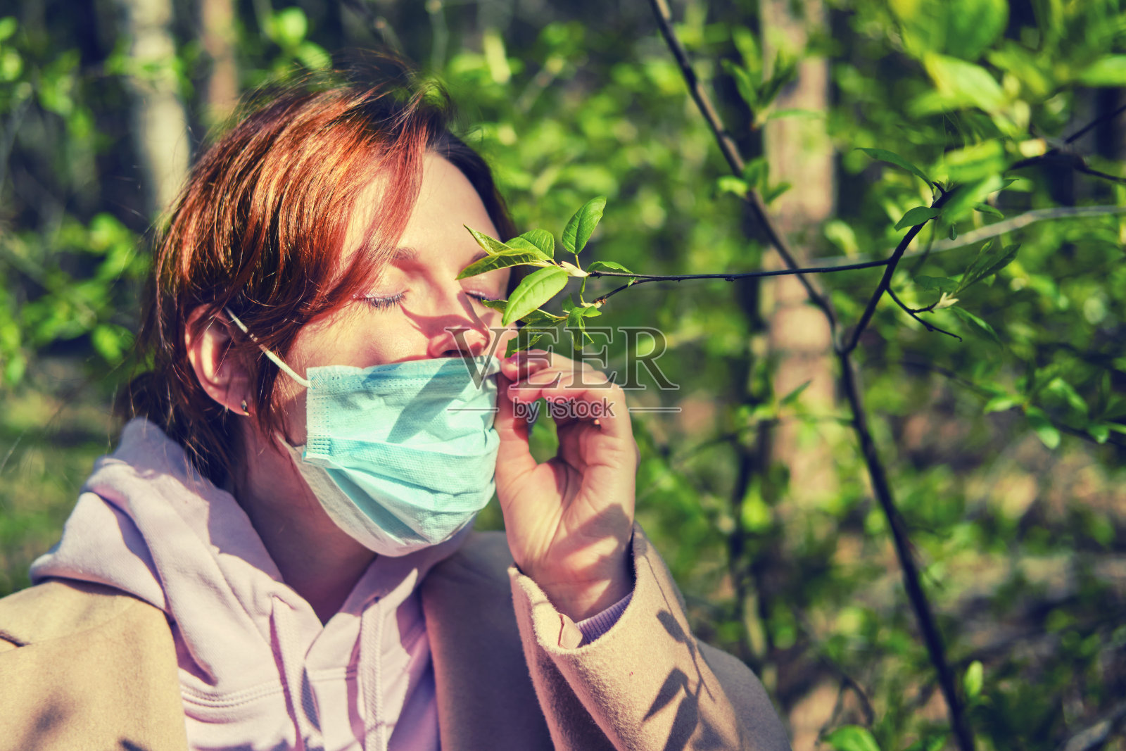一名女子在一棵绿叶树附近被隔离后摘下了医用口罩照片摄影图片