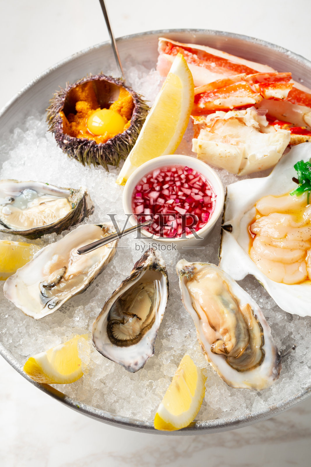 大盘菜，搭配新鲜的海鲜冰-牡蛎，海胆，扇贝和螃蟹。近距离观看海鲜与柠檬片和酱油。餐厅里的海鲜和碎冰盘照片摄影图片