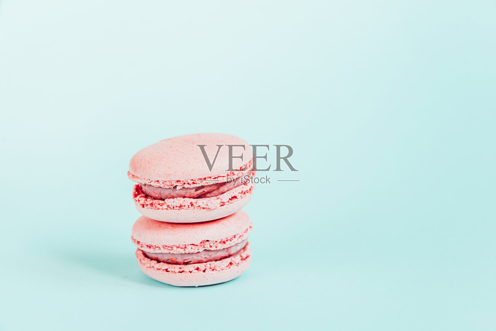 甜杏仁彩色独角兽粉马卡龙或马卡龙甜点蛋糕孤立在时尚的蓝色柔和背景。法国甜的饼干。最小的食品烘焙概念拷贝空间照片摄影图片