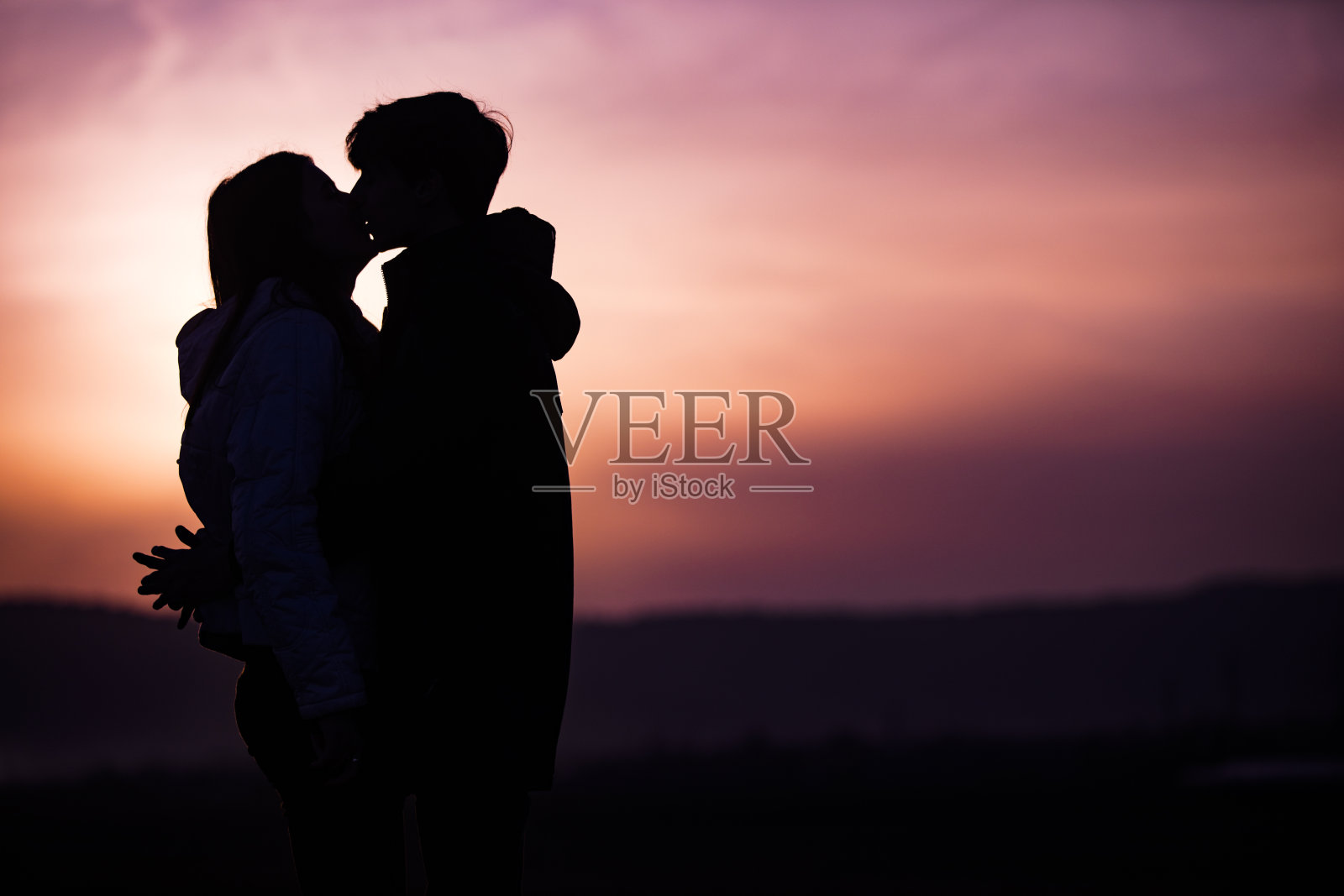 一对青少年情侣在日落时分接吻照片摄影图片