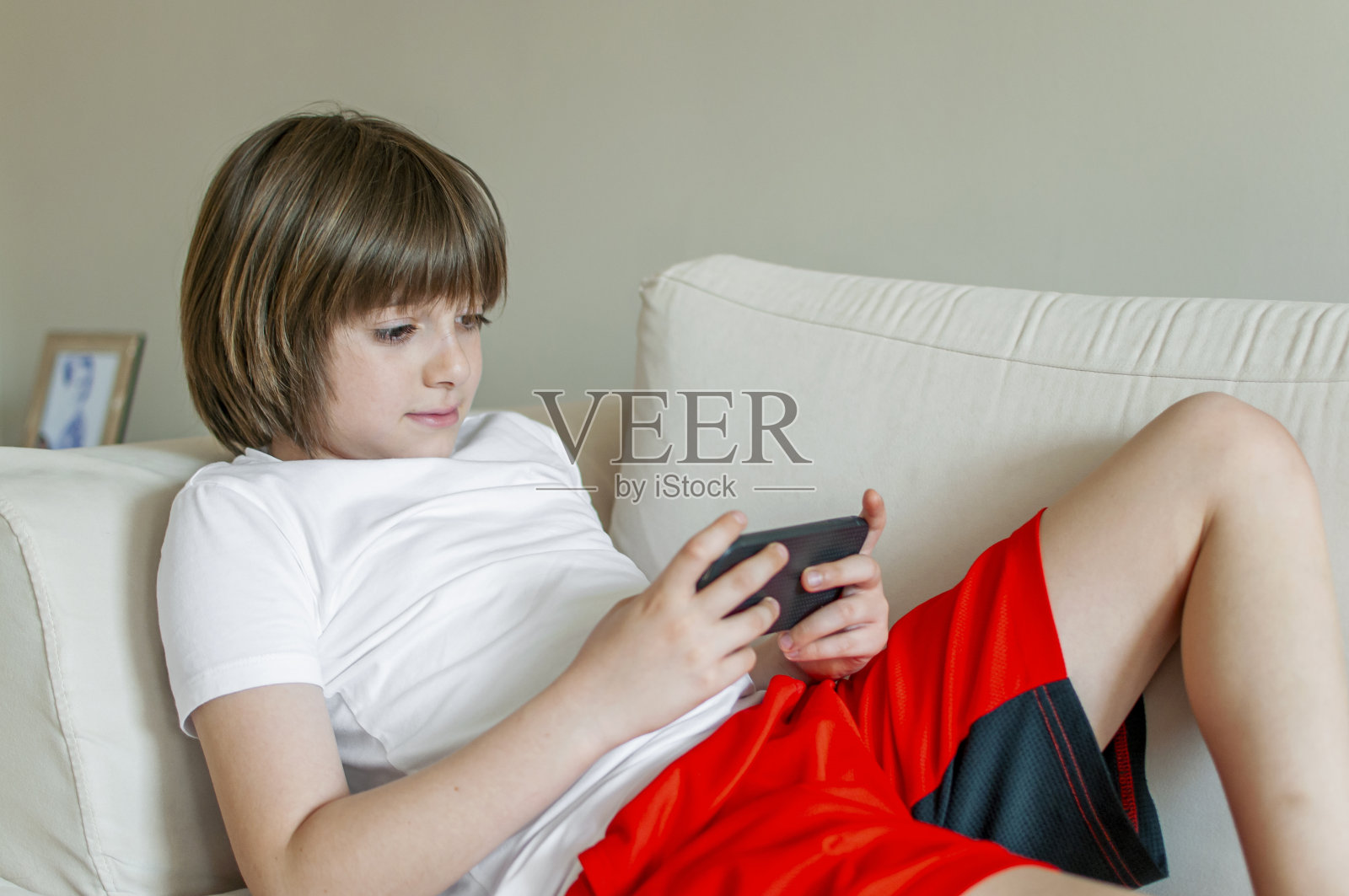 可爱的男孩在家里用手机照片摄影图片
