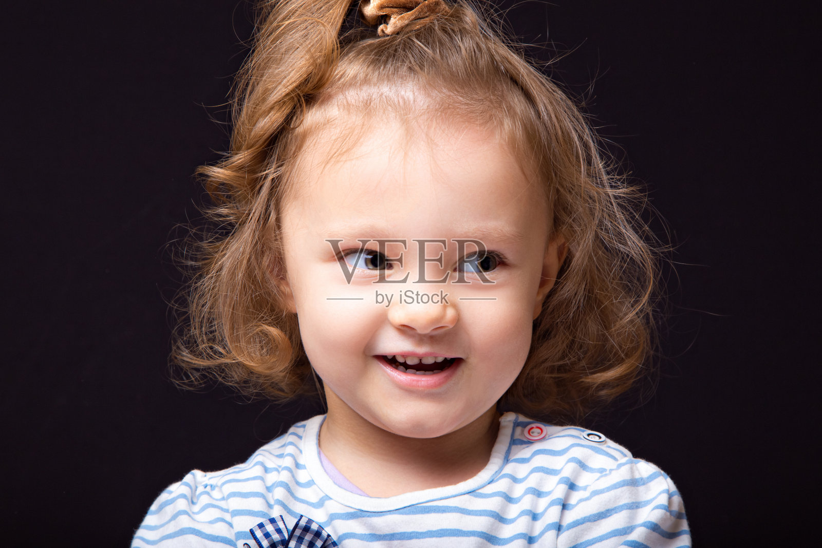 微笑快乐的小女孩与鬼脸看和决定的问题在黑色演播室背景。特写镜头照片摄影图片