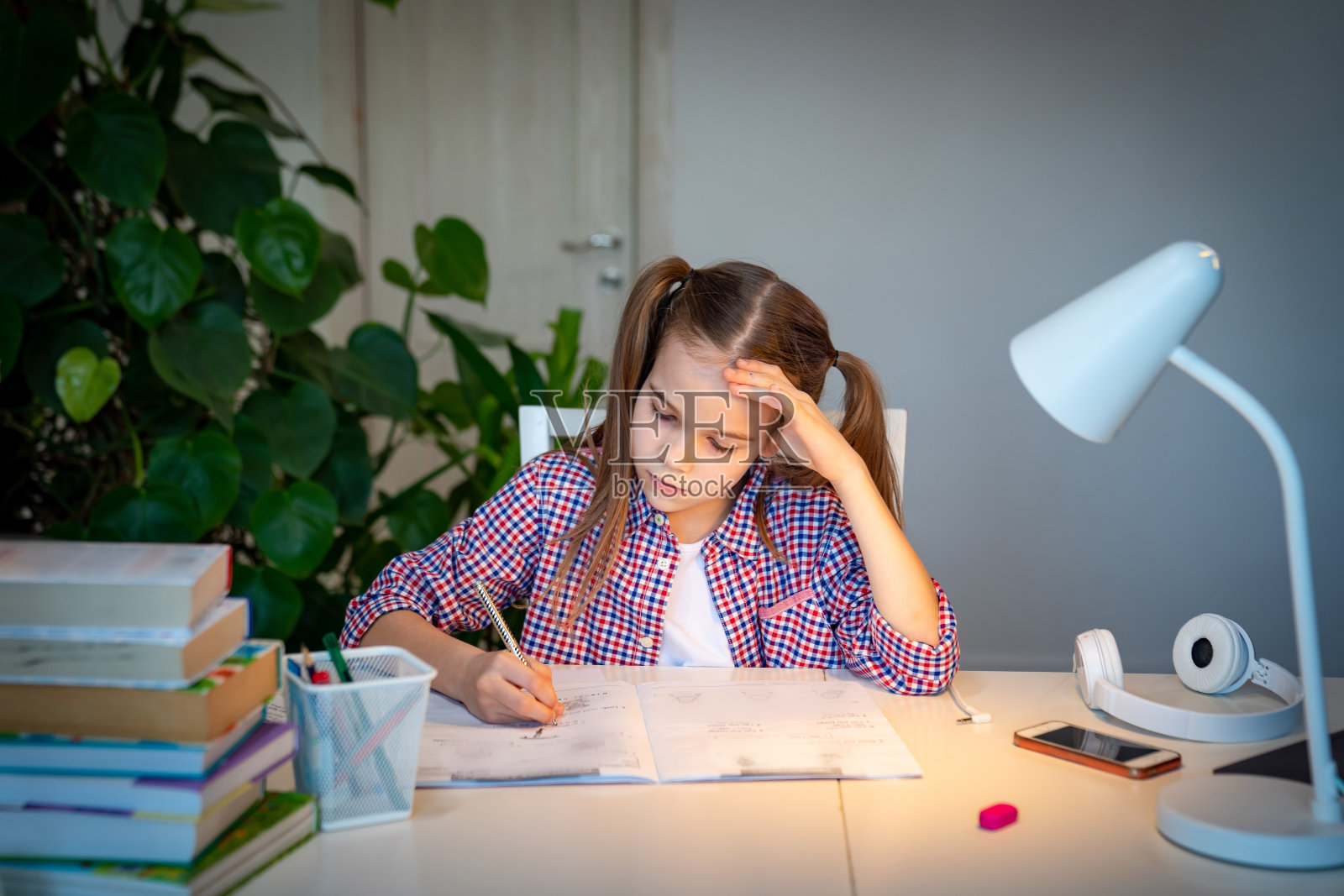 悲伤的女孩在做作业。在家学习照片摄影图片