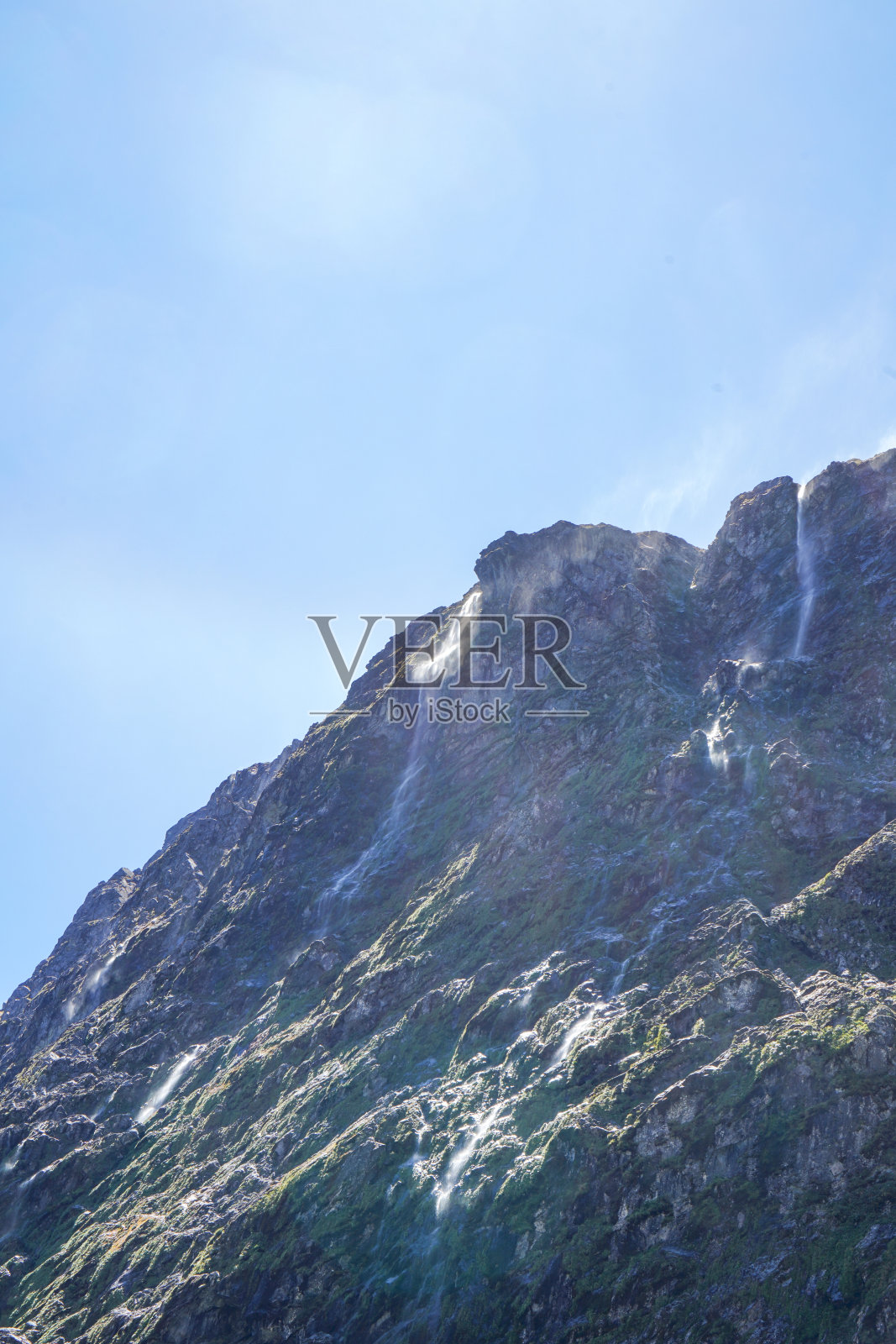 草地和悬崖瀑布靠近荷马隧道在米尔福德湾，新西兰南部照片摄影图片