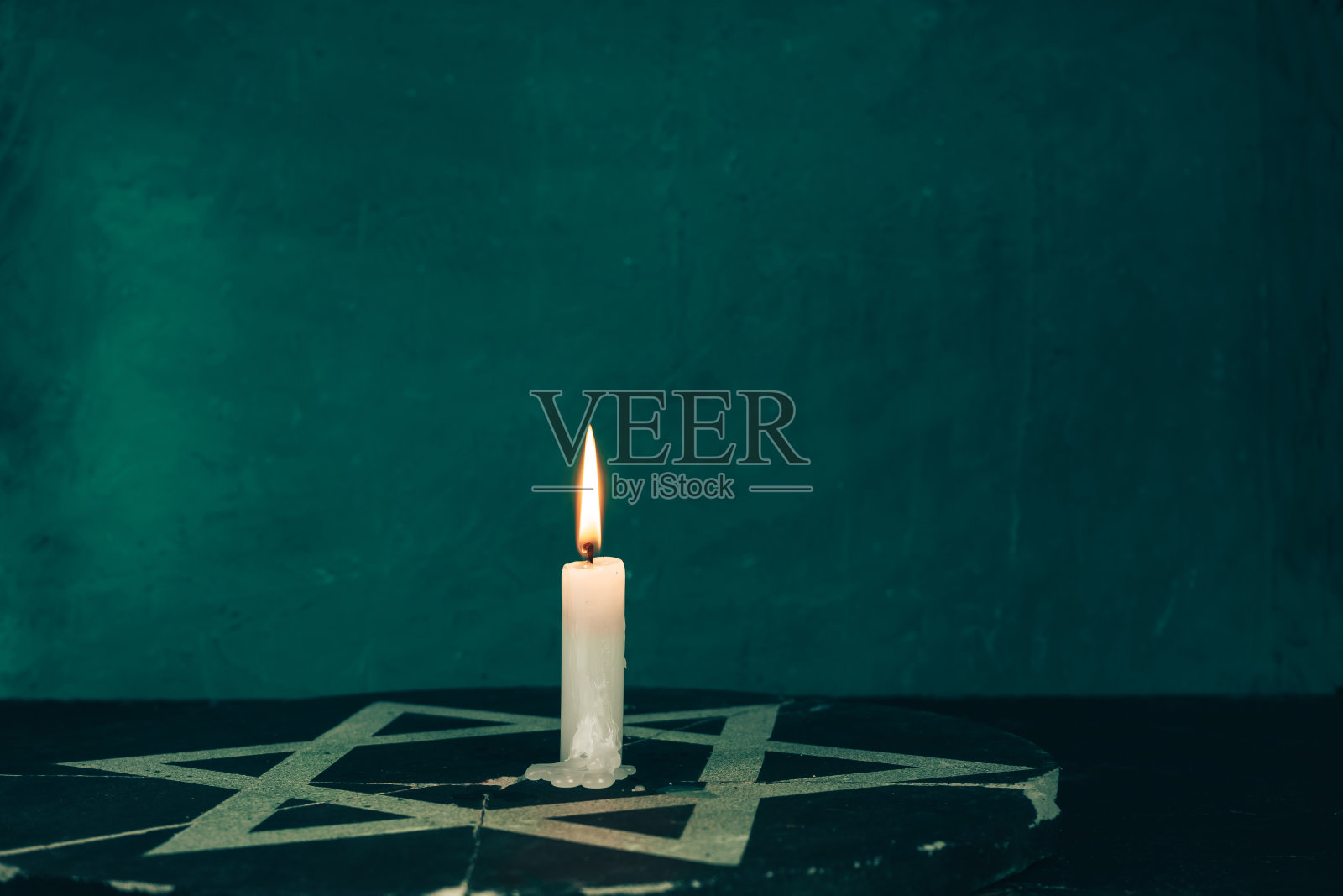 燃烧的蜡烛和六芒星特写，绿色背景墙照片摄影图片