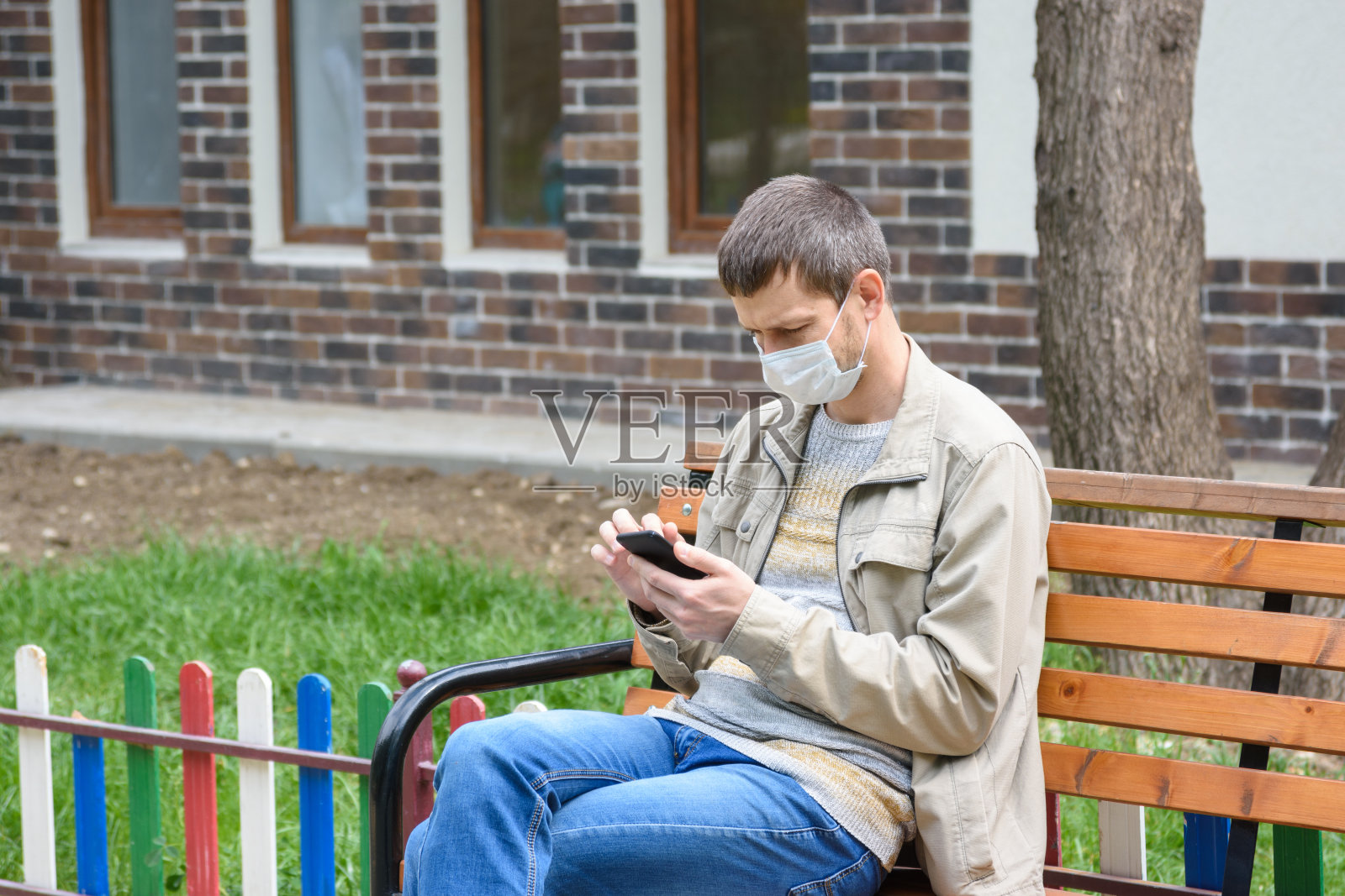 街上一个男人蹲在长凳上看手机屏幕照片摄影图片