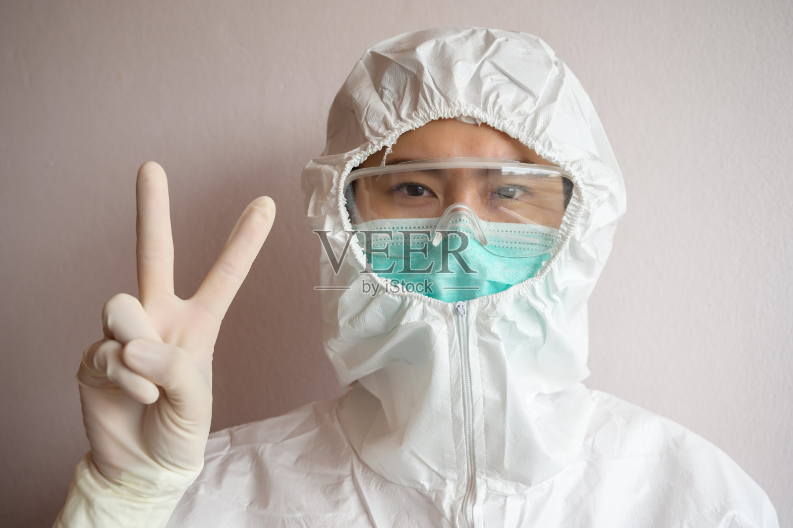 护士穿防护服，戴口罩，保护病毒，显示胜利。照片摄影图片