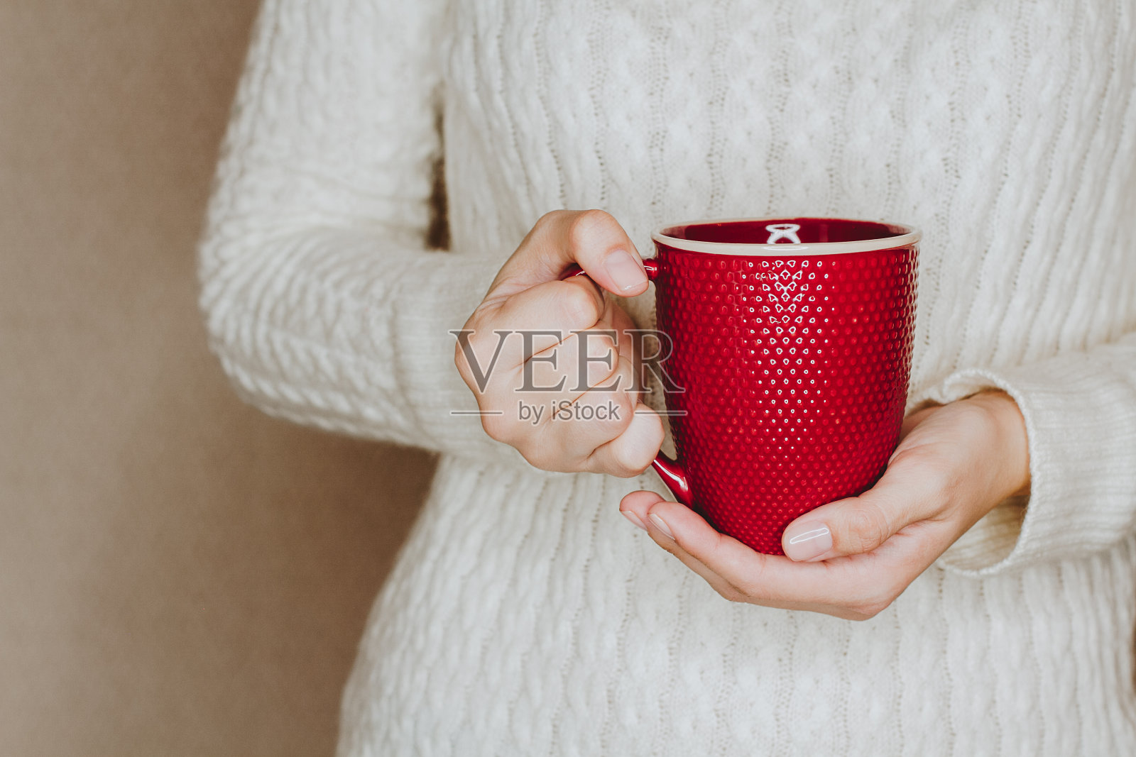 穿着白毛衣的年轻女子正拿着一杯红茶或咖啡。照片摄影图片
