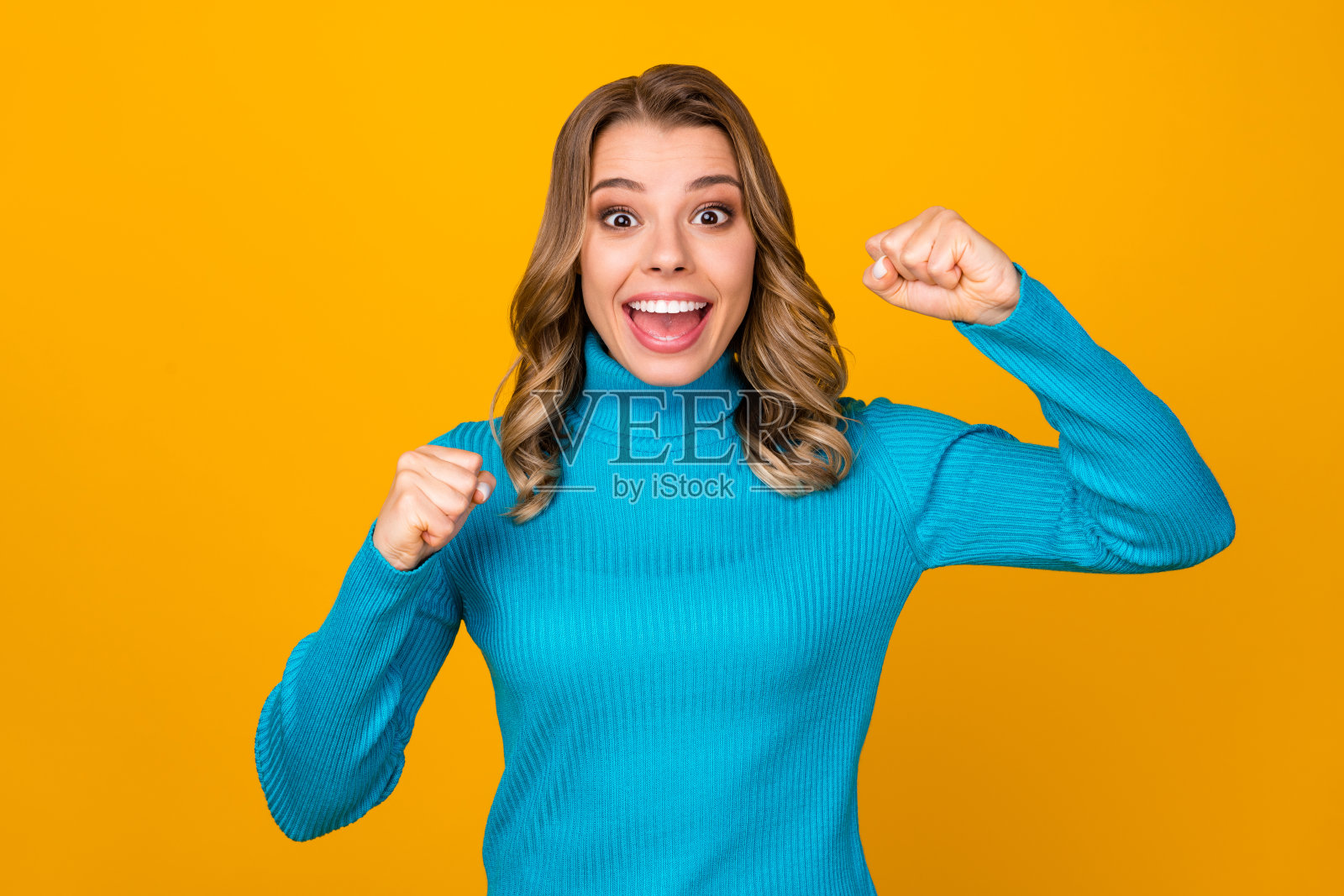迷人的照片疯狂有趣的卷发女士兴奋地支持运动队举起拳头欢呼的球员穿休闲蓝色温暖的高领孤立亮黄色背景照片摄影图片