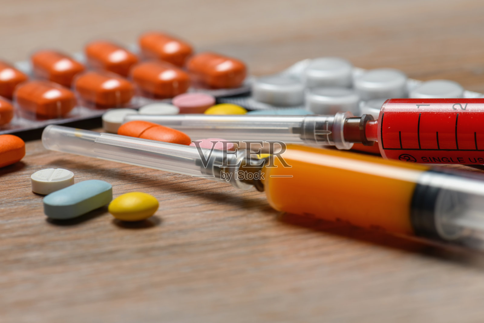 COVID - 19病毒感染治疗方案的概念。彩色注射器和药片特写。照片摄影图片