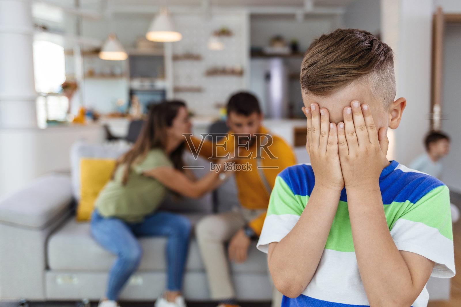 父母争吵时，恼怒的男孩捂着眼睛照片摄影图片