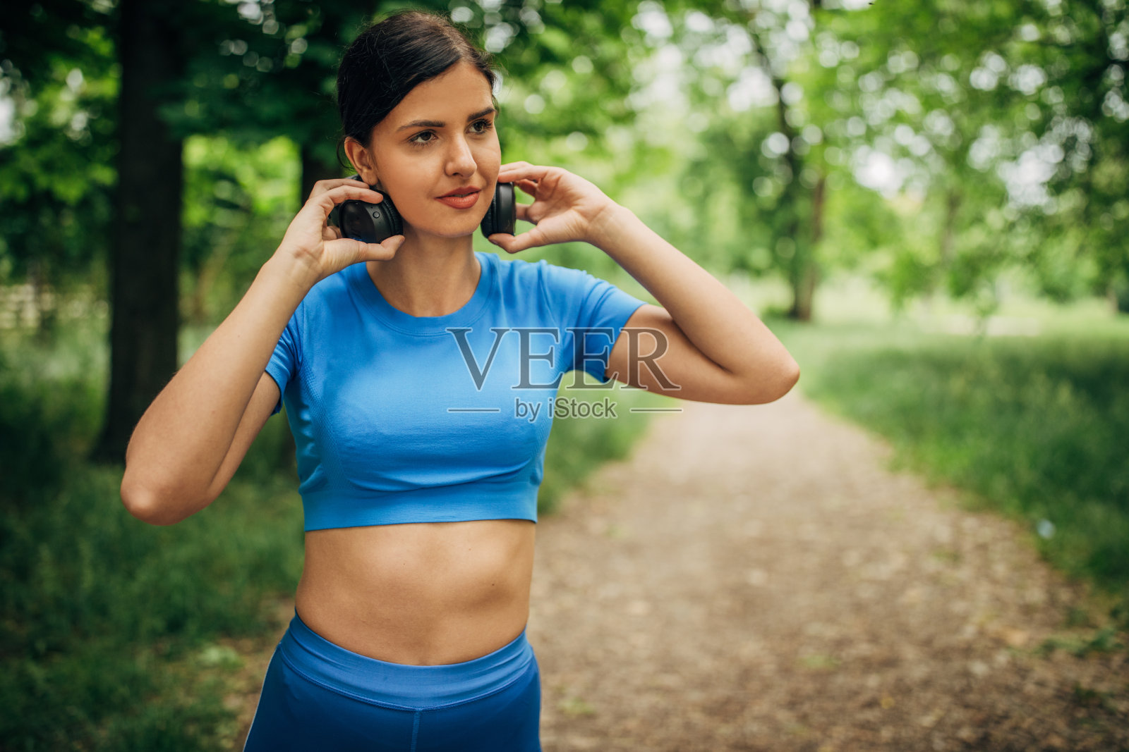 年轻漂亮的女人在公园里戴着耳机听音乐照片摄影图片