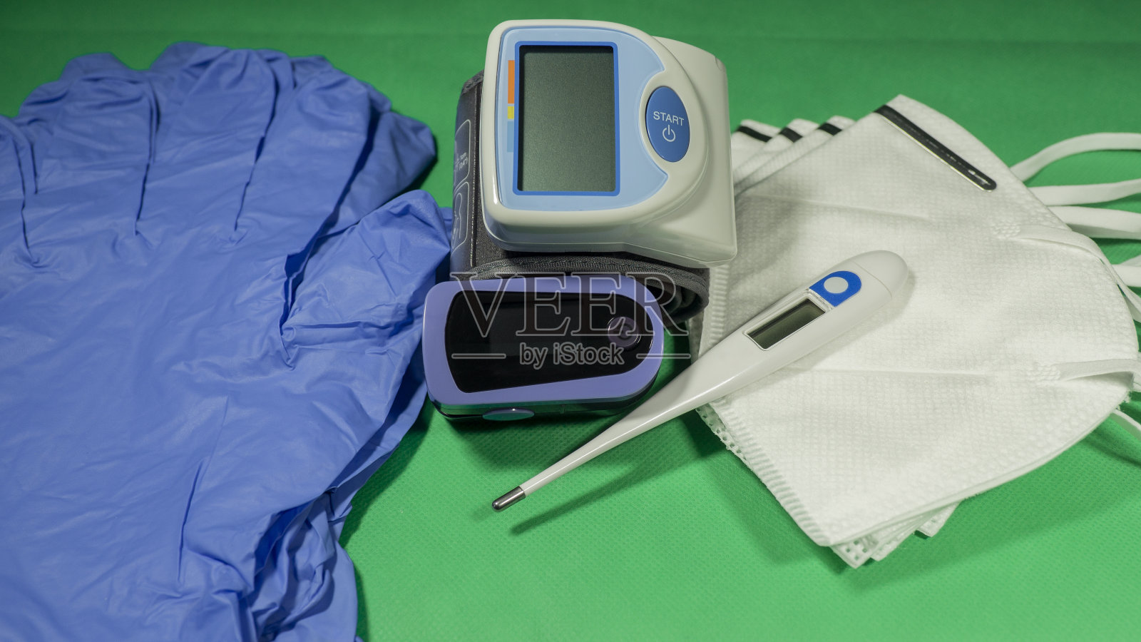 医疗包:数字体温计、脉搏血氧计、医用口罩、手臂血压计。一次性医用手套。用于检测冠状病毒感染的试剂盒。绿色背景照片摄影图片