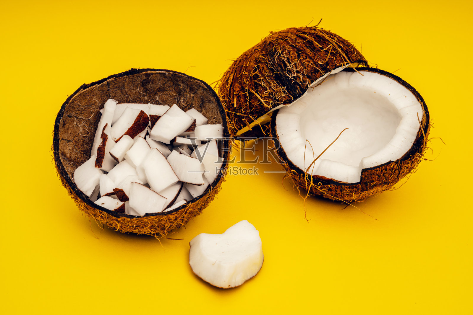 椰子的一部分在一个彩色的背景。关闭了。新鲜成熟的椰子碎成碎片。照片摄影图片