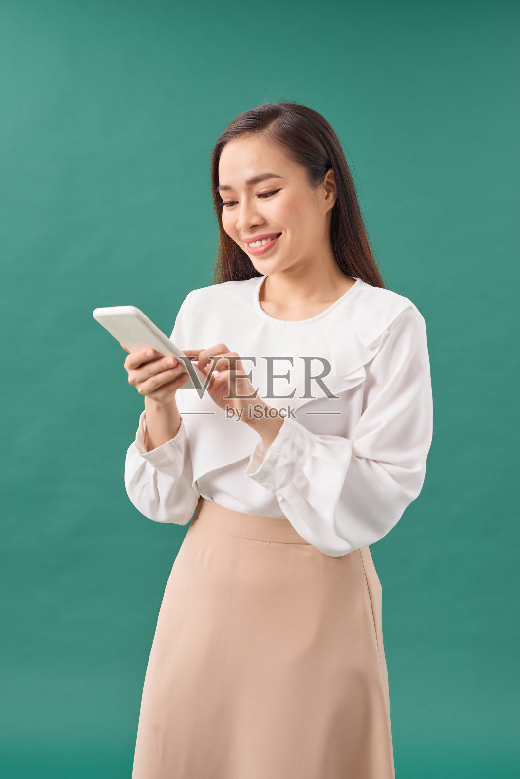 微笑的年轻女子女孩使用手机输入短信蓝绿色的背景。照片摄影图片