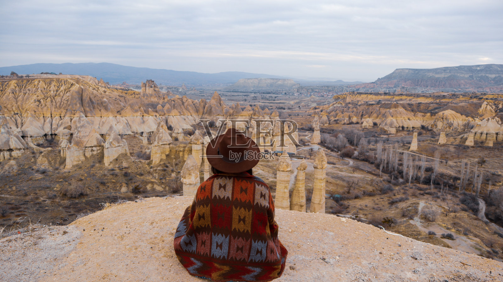 在土耳其卡帕多西亚的爱谷，一个女人独自看着蘑菇形状的仙女烟囱。照片摄影图片
